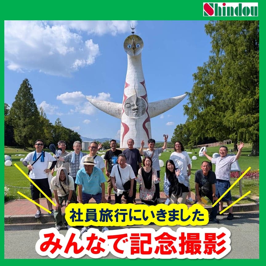 太陽の塔の前で「芸術は爆発だ!」をイメージしたポーズで記念撮影する社員のみなさん